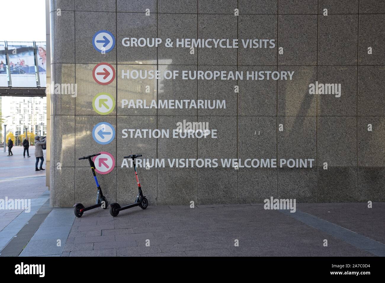 Dockless louer des scooters électriques stationné à côté de la direction de panneaux aux bâtiments du Parlement européen, Bruxelles, Belgique Banque D'Images