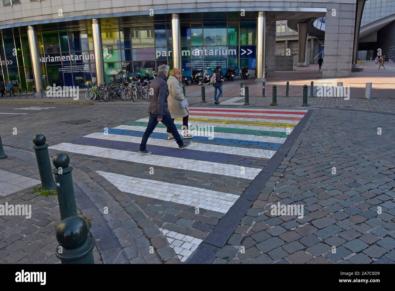 Les personnes qui franchissent un passage pour piétons en couleurs fierté devant le Parlement européen, Bruxelles, Belgique Banque D'Images