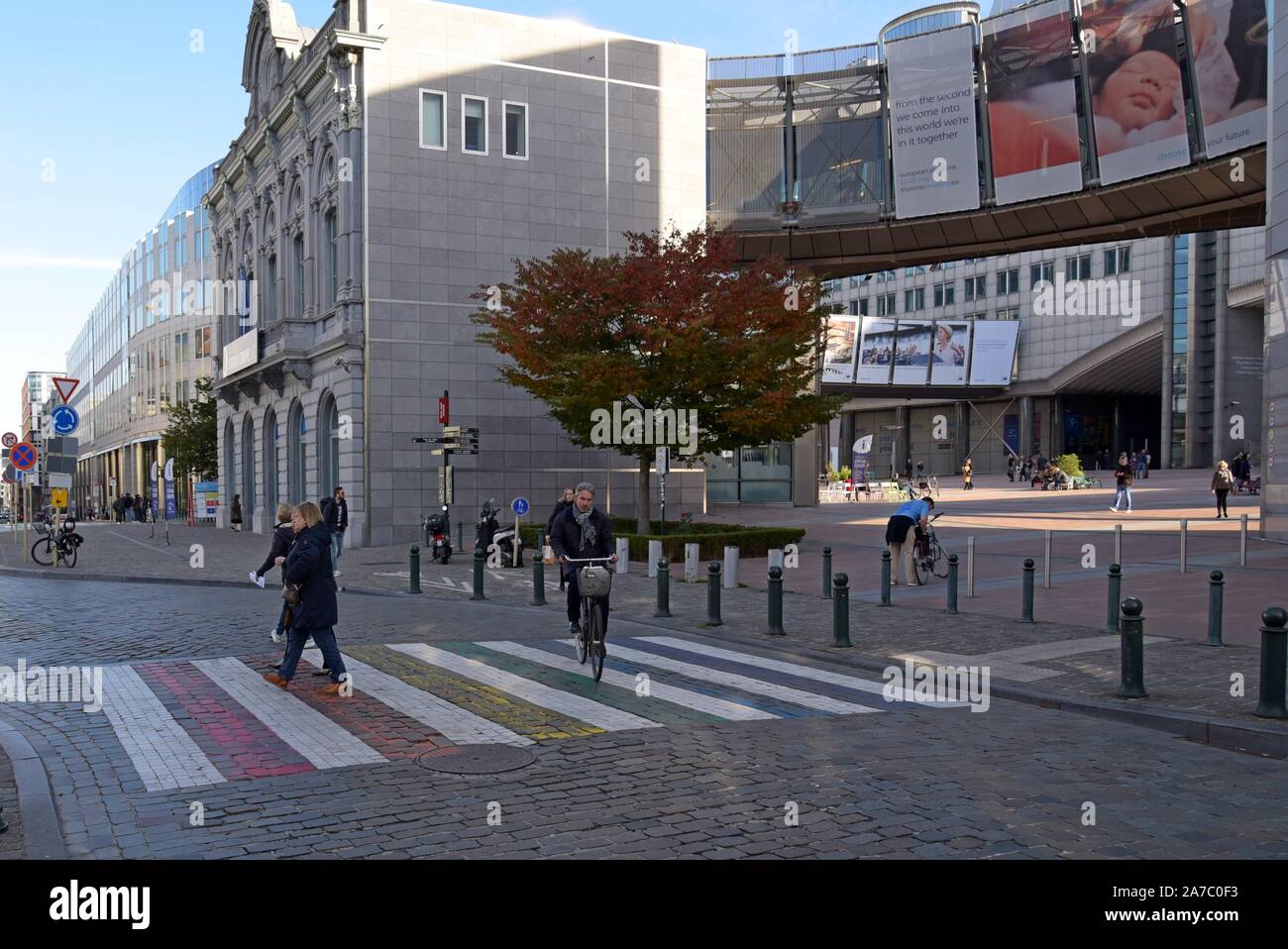 Les personnes qui franchissent un passage pour piétons en couleurs fierté devant le Parlement européen, Bruxelles, Belgique Banque D'Images