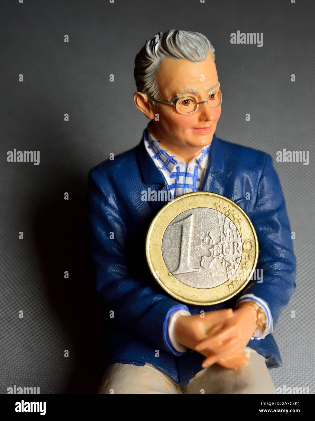 Pensionné, figurine holding 1 euro coin Banque D'Images