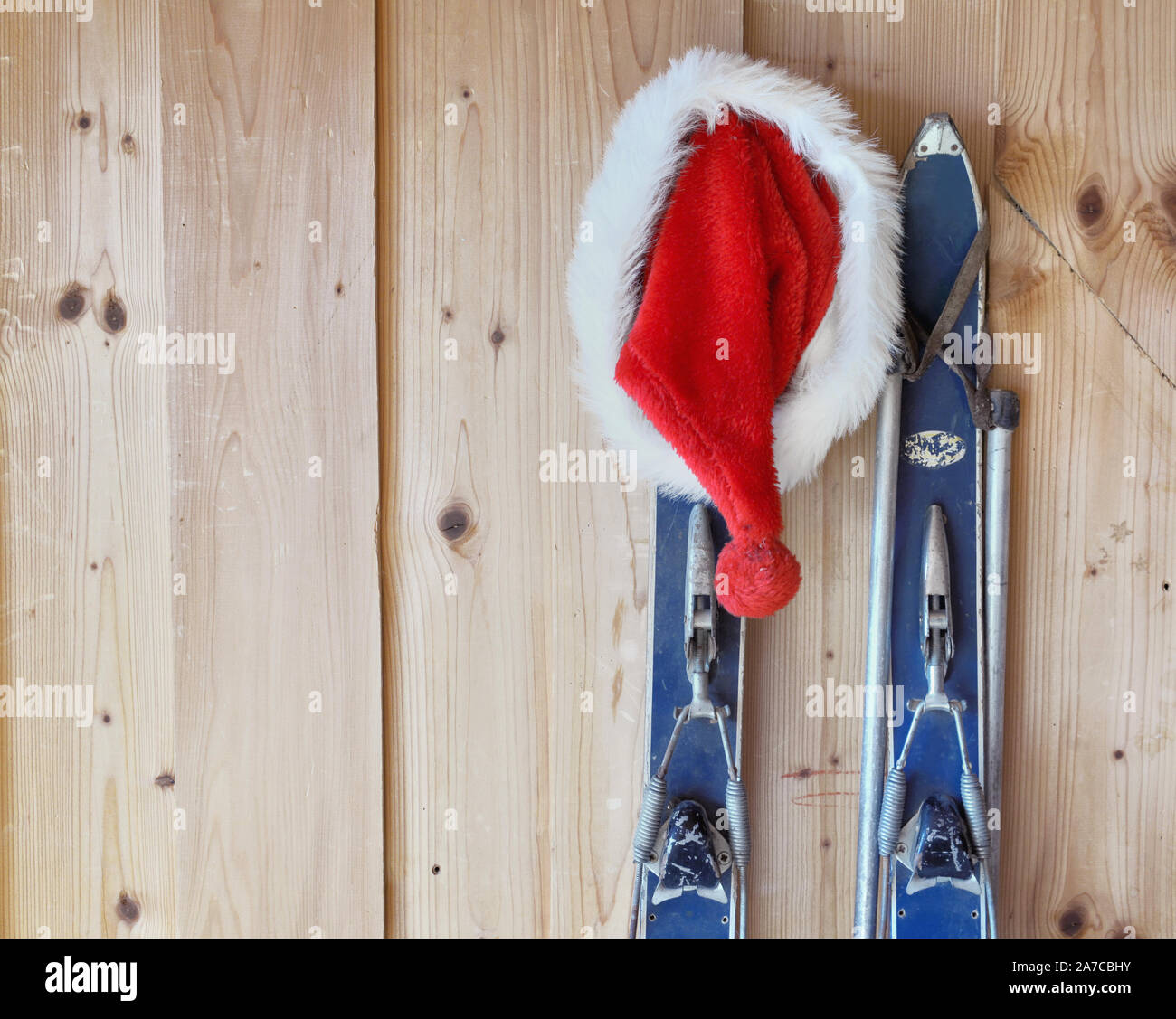 Cap de santa claus accrochée à un vieux contre un mur en bois de ski dans un chalet Banque D'Images