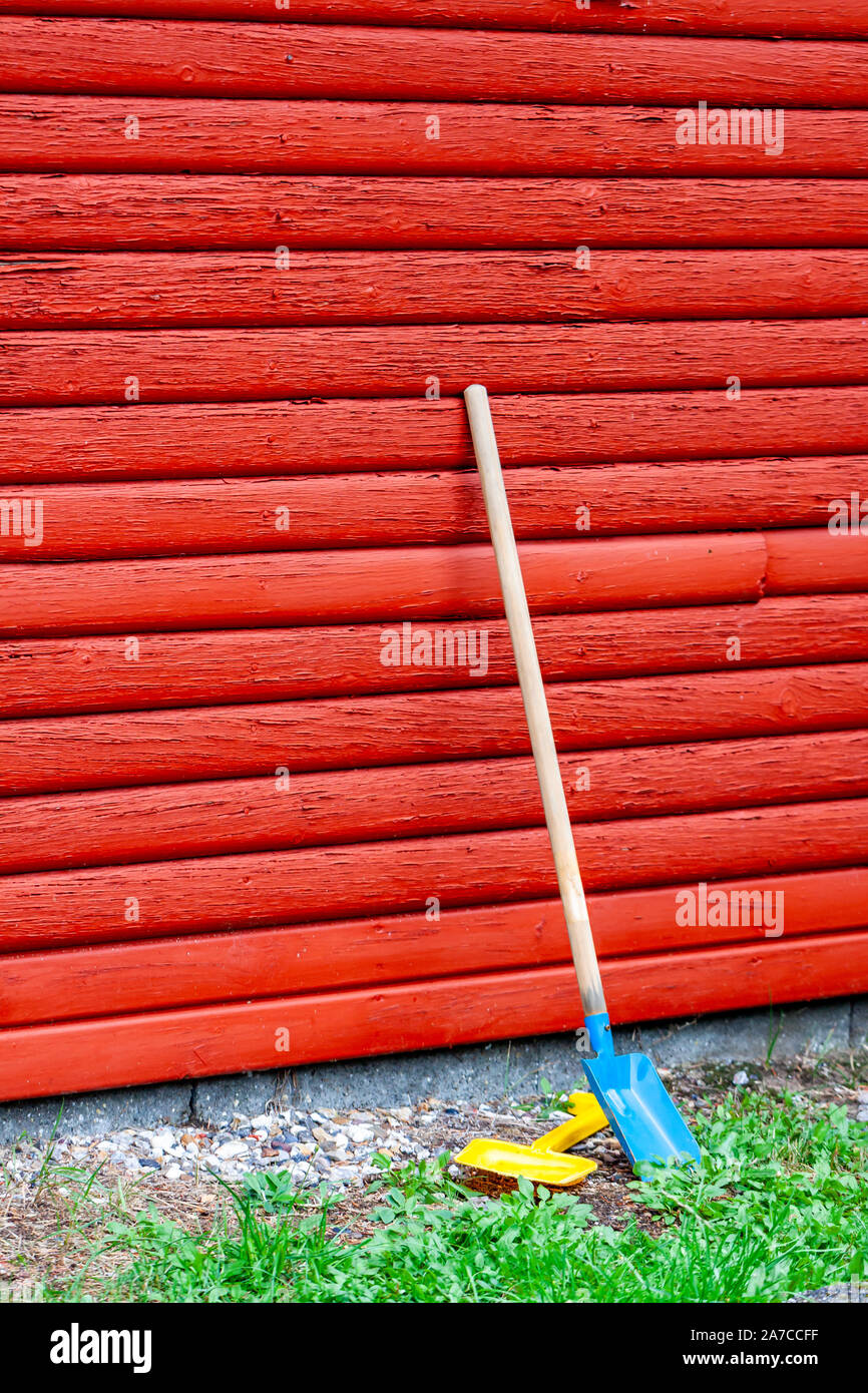 Toy pelle et vague debout à côté d'un mur en bois rouge. Banque D'Images