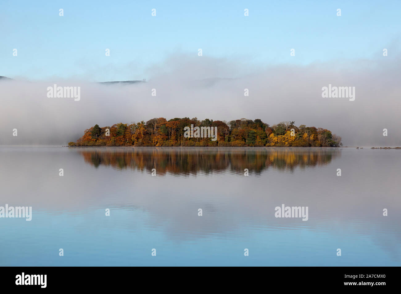 Tôt le matin dans la région de Derwent Water Parc National de Lake District en Angleterre. Brume sur le lac, enveloppant une petite île. Banque D'Images