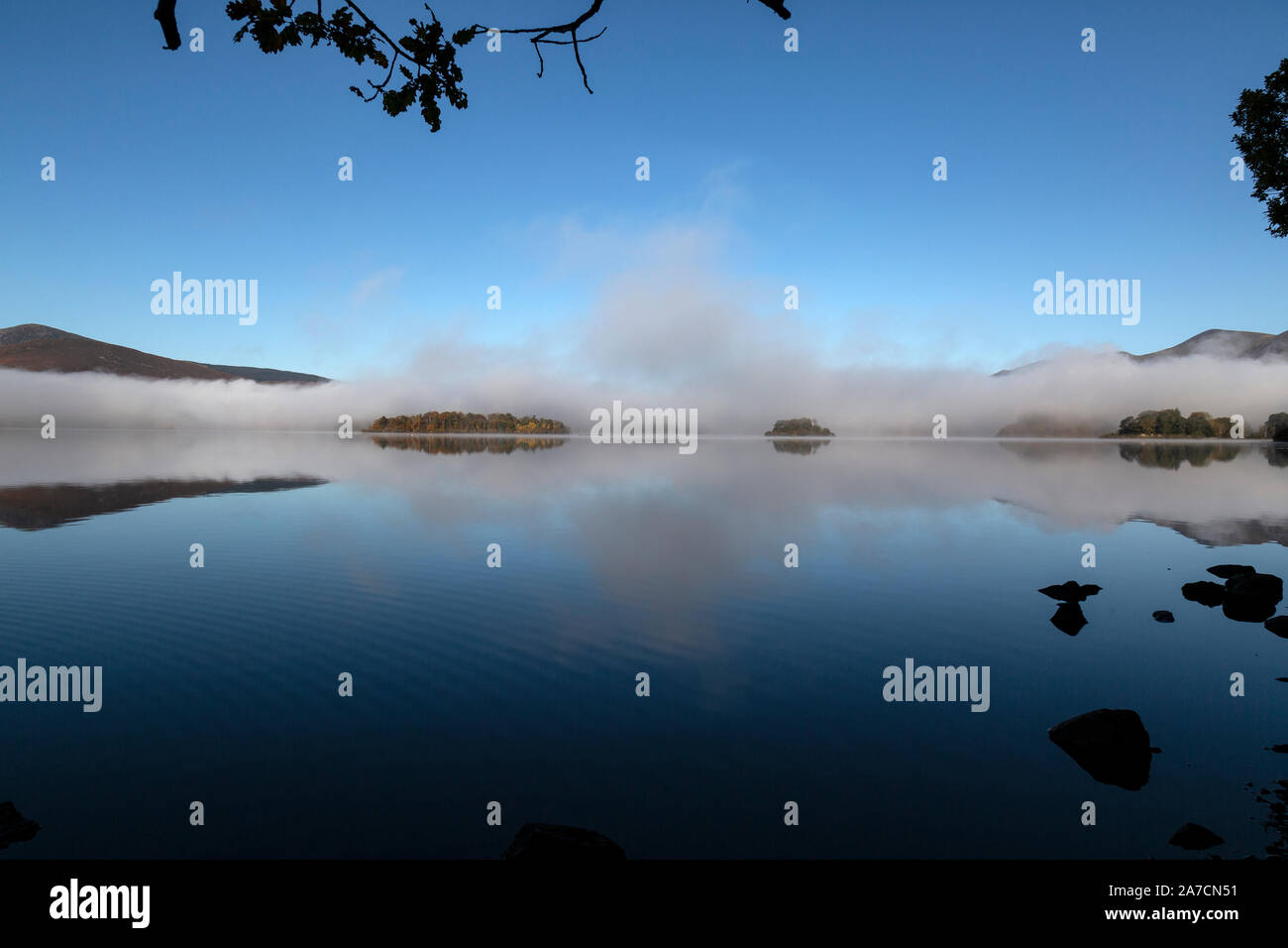 Tôt le matin dans la région de Derwent Water Parc national de Lake District en Angleterre. Brume sur le lac, enveloppant deux petites îles. Banque D'Images