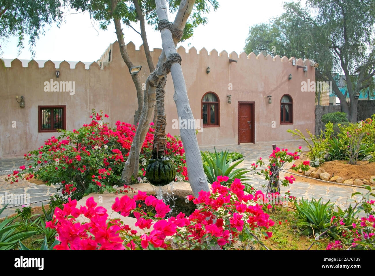 Maison traditionnelle en pierre et bien dans le jardin de devant à l'Heritage Village, Abu Dhabi, Emirats Arabes Unis. Banque D'Images