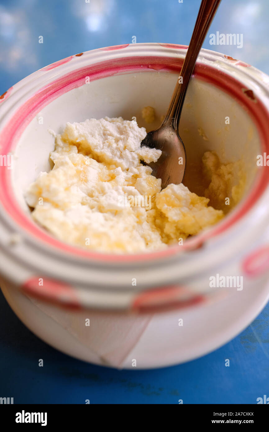 Ricotta Salata réfrigérées fraîchement préparés et le miel dans un bol en céramique avec cuillère sur un tableau bleu top - petit-déjeuner dessert fromage ricotta Banque D'Images
