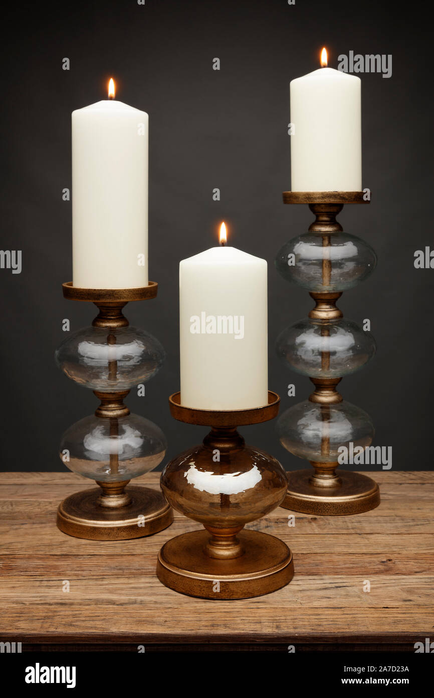 3 chandeliers en verre et de bougies, tourné sur une table en bois, avec un fond gris foncé Banque D'Images