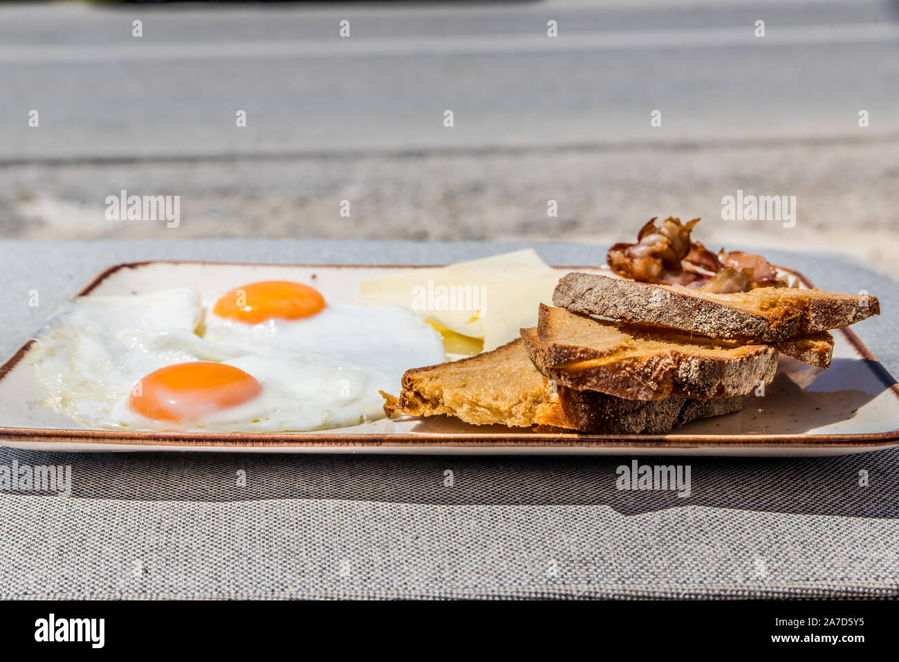 Une assiette de petit-déjeuner avec des œufs, tomate, pain, fromage et bacon graviera Banque D'Images