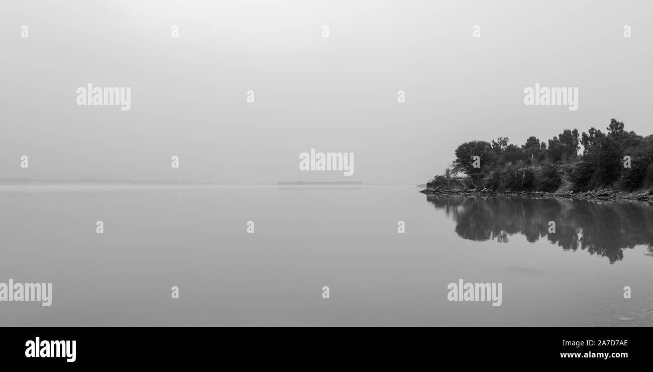 Matin brumeux en noir et blanc et de réflexion des arbres dans le Lac de Barrage de Tarbela Ghazi Banque D'Images