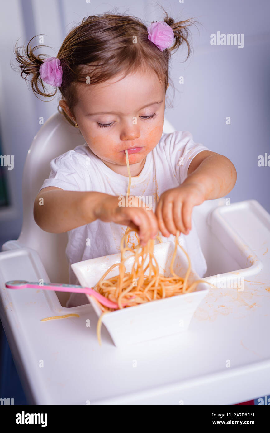Adorable petit 1 ans, fille, bébé, enfant, assis dans un fauteuil à la  maison, mange les mains, nouilles photo in real life l'intérieur, de  l'allaitement d'hiver Photo Stock - Alamy