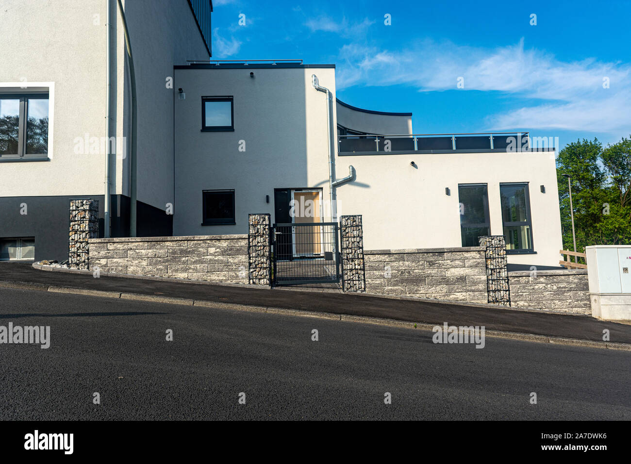 Nouvelle maison avec une clôture en pierre contre le ciel bleu 24 Banque D'Images