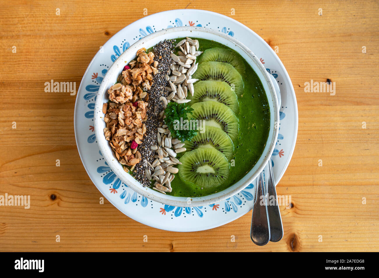 Smoothie déjeuner bol, : kiwi, semences chia, de tournesol et de courge sur une boule blanche. Repas santé populaires, sur table en bois brun clair. Banque D'Images