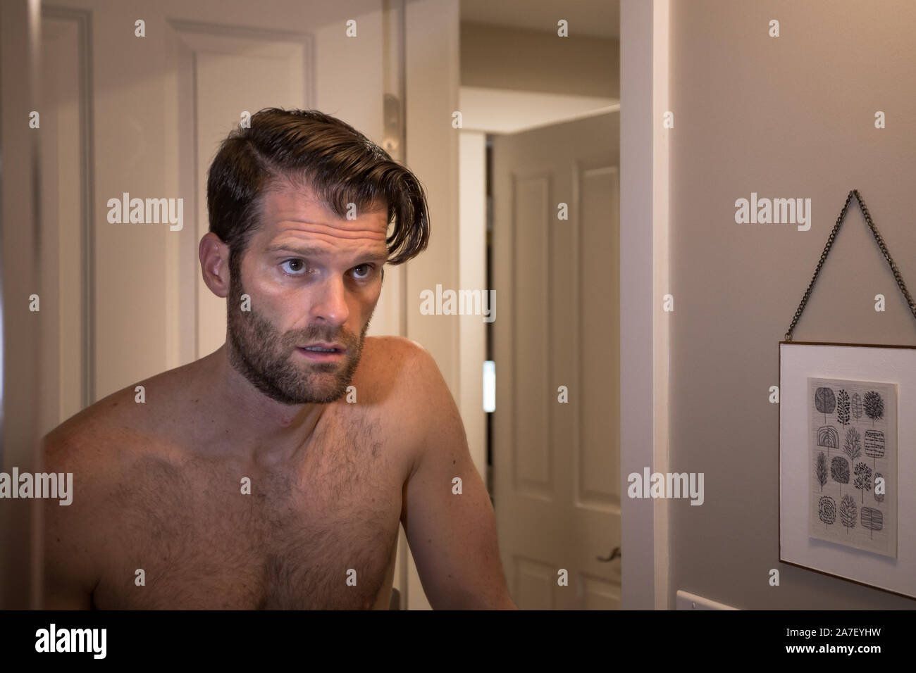 Un homme de race blanche d'âge moyen avec une expression malheureuse se regardant dans un miroir. Banque D'Images