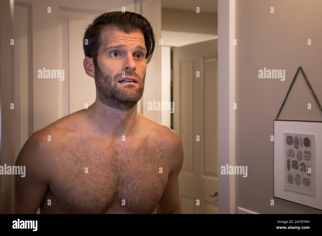 Un homme de race blanche d'âge moyen avec une expression malheureuse se regardant dans un miroir. Banque D'Images