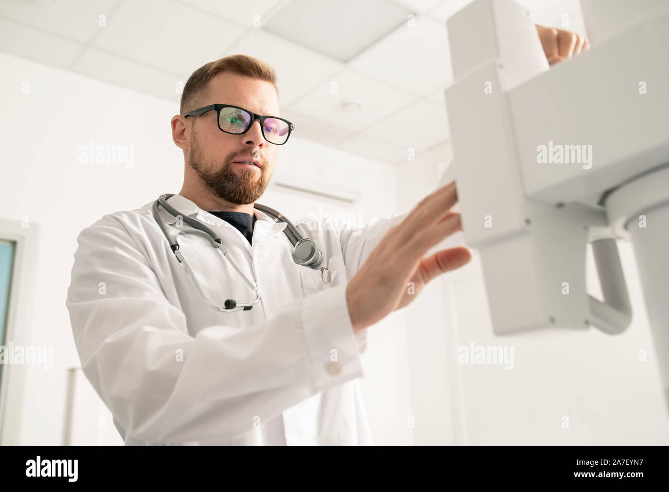 Jeune médecin barbu debout en face de l'équipement médical contemporain Banque D'Images