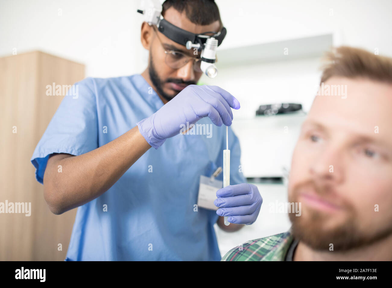 Jeune médecin sérieux dans les gants médicaux mettre stick dans la fiole avant traitement Banque D'Images