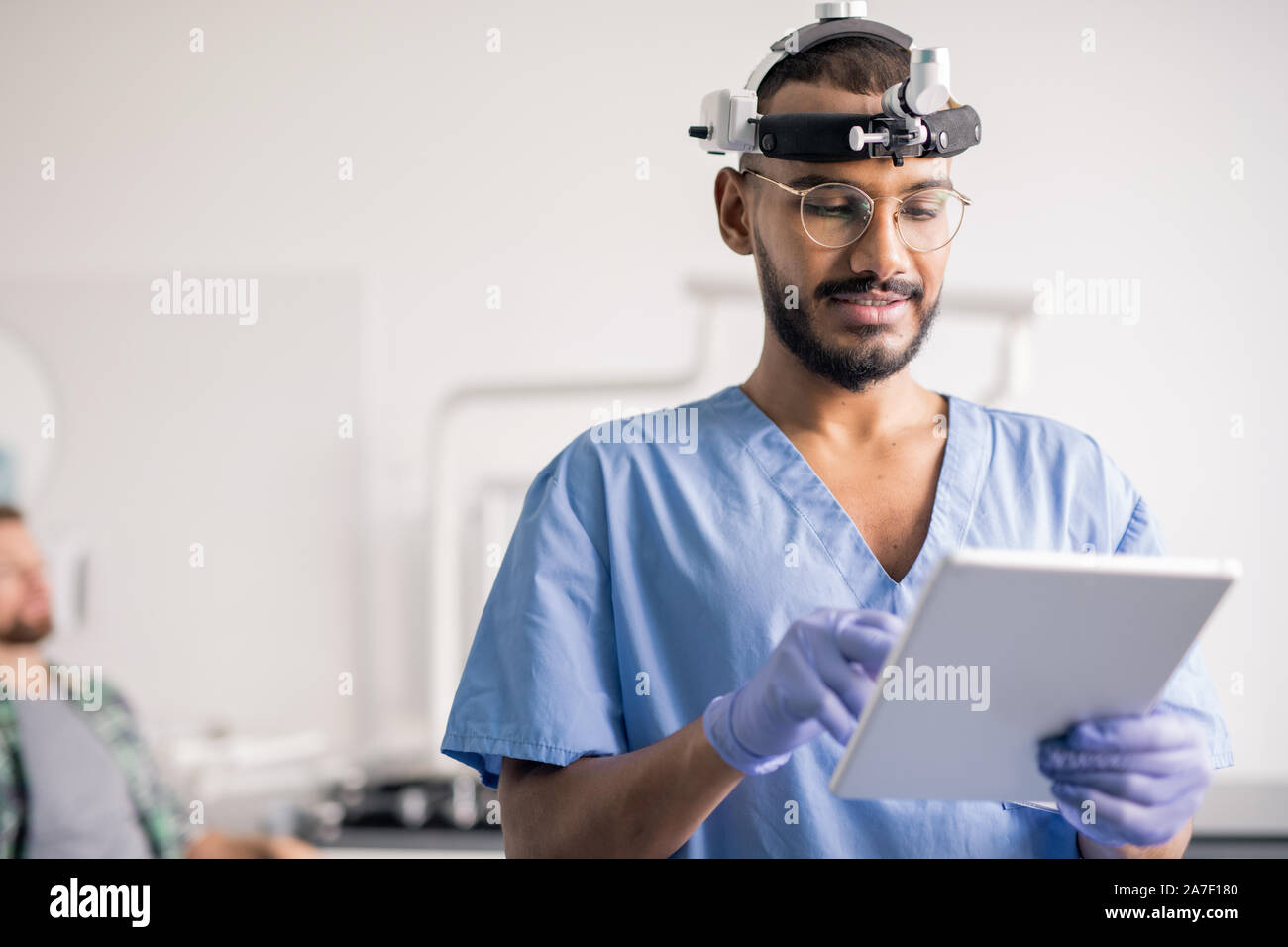 Clinicien/clinicienne en uniforme et l'équipement médical sur la tête du défilement des données en ligne Banque D'Images