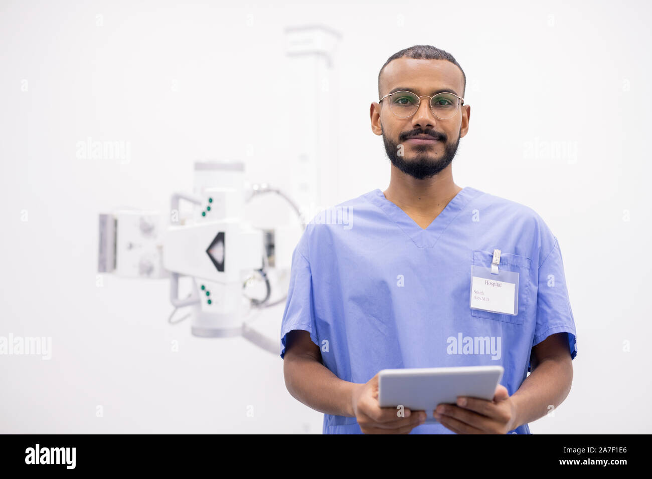Jeune stagiaire de race mixte barbu en uniforme et lunettes en utilisant le pavé tactile Banque D'Images