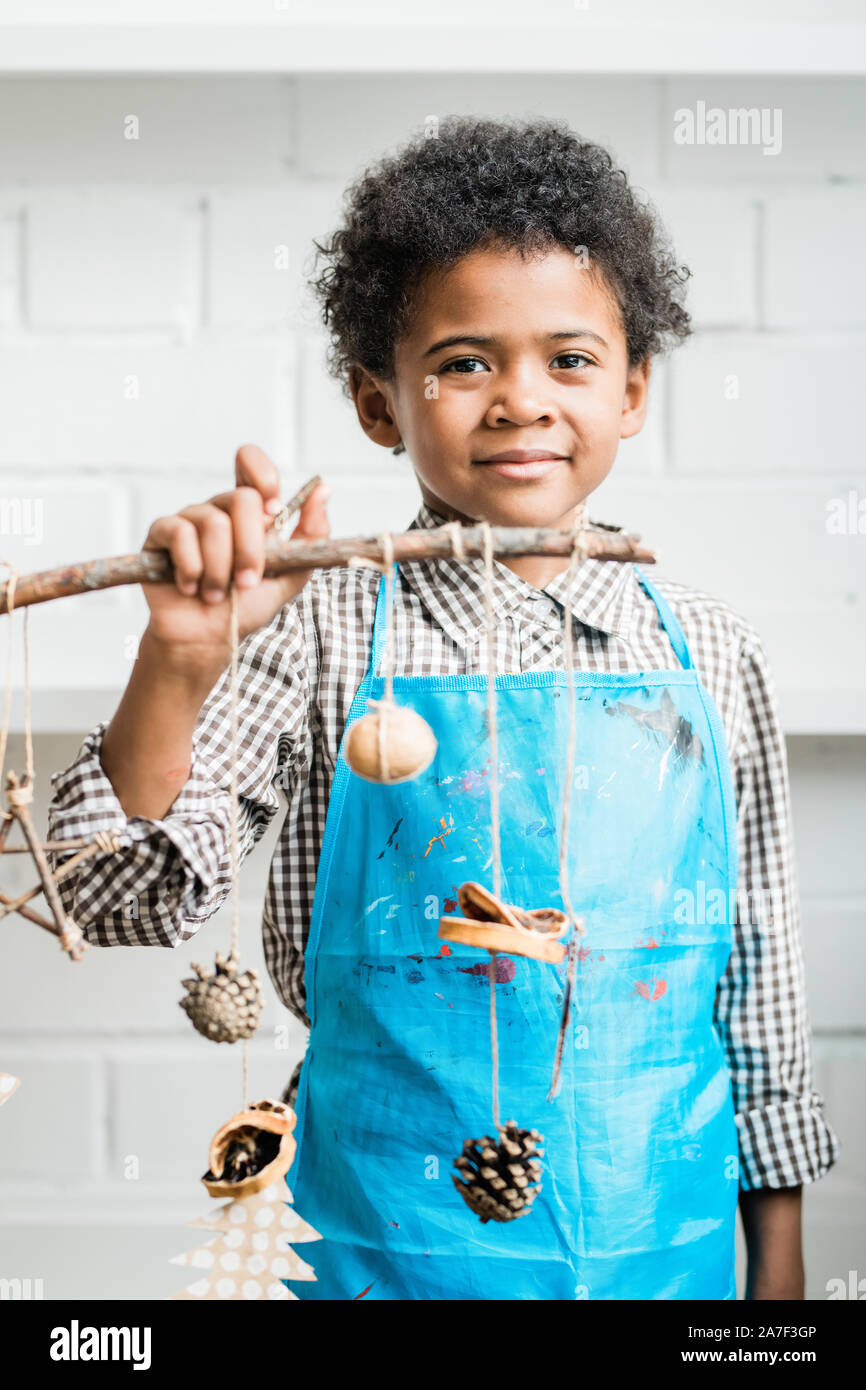 L'Afrique de l'heureux jeune en tablier bleu holding stick avec des décorations faites à la main Banque D'Images