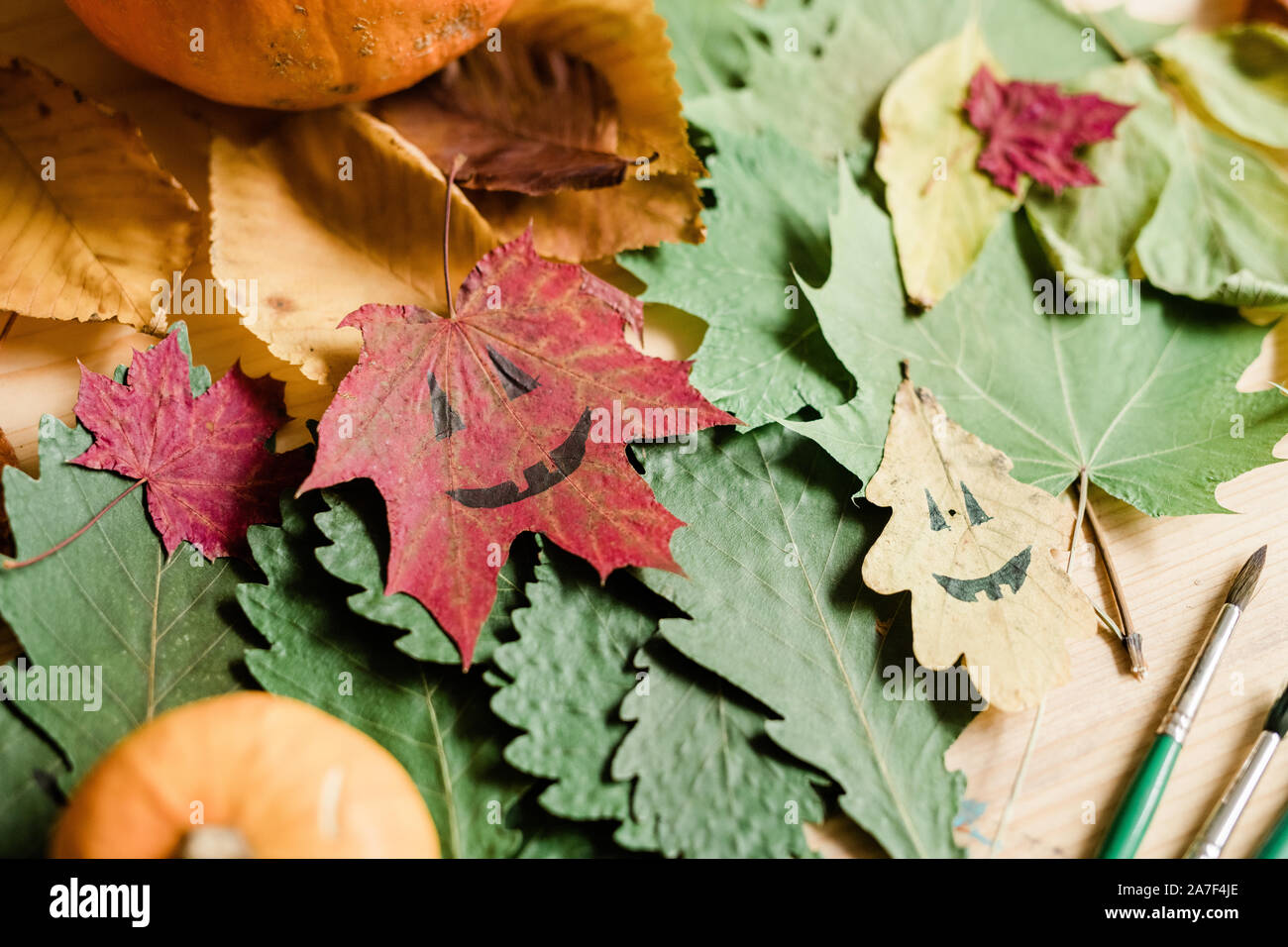 Arrière-plan de l'automne, le feuillage sec visages halloween sur les feuilles et pinceaux Banque D'Images