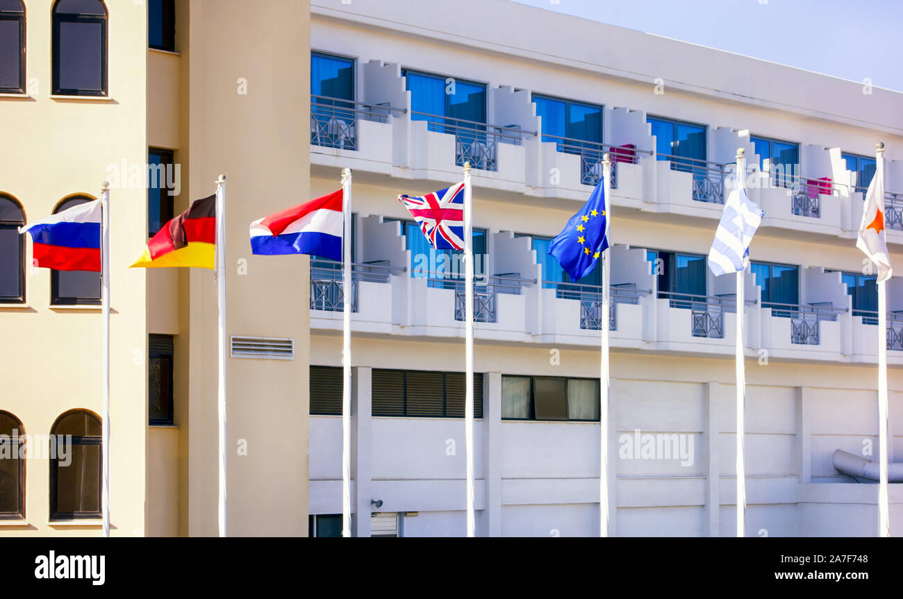 Russe, Néerlandais, Allemand, Anglais, Grec, de Chypre, de l'Union européenne Les drapeaux sur hampes de voltigeant dans le vent en face de l'hôtel Banque D'Images