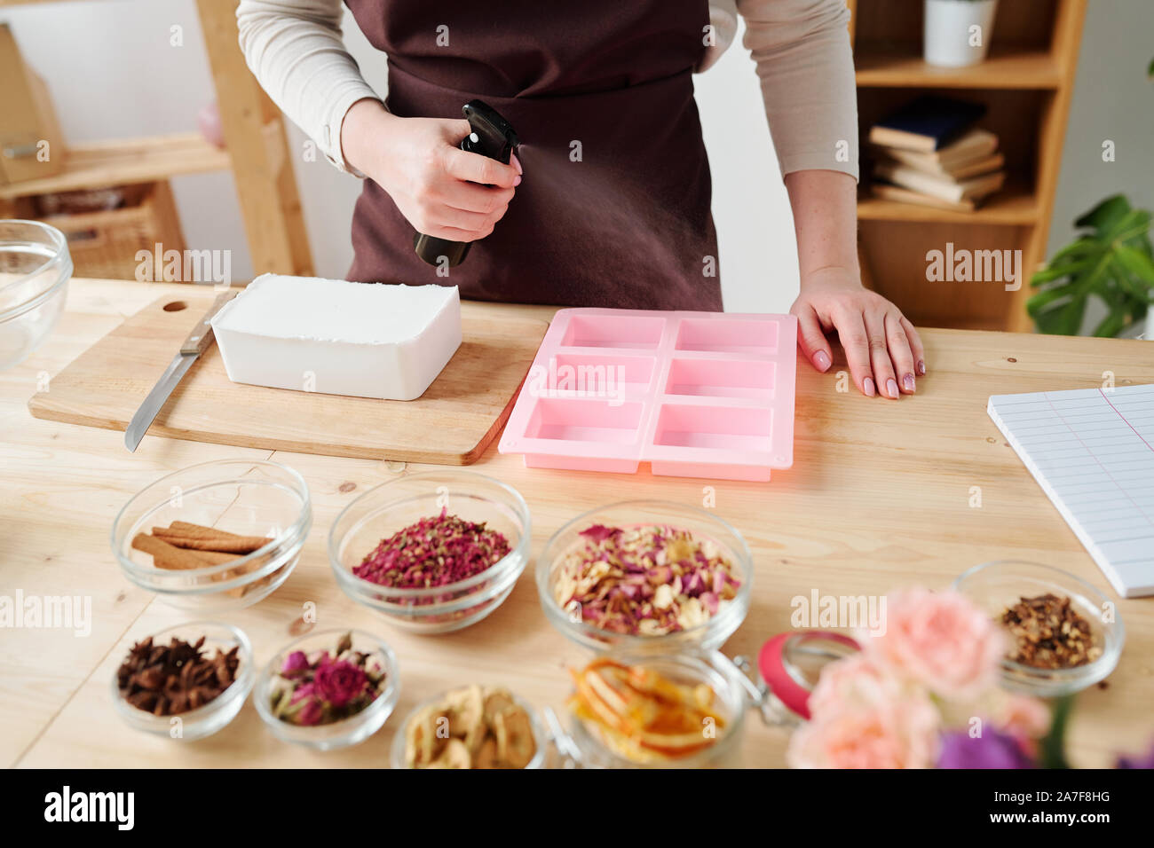 Jeune artisane de pulvériser les moules en silicone sur l'huile avant de verser la masse de savon liquide Banque D'Images