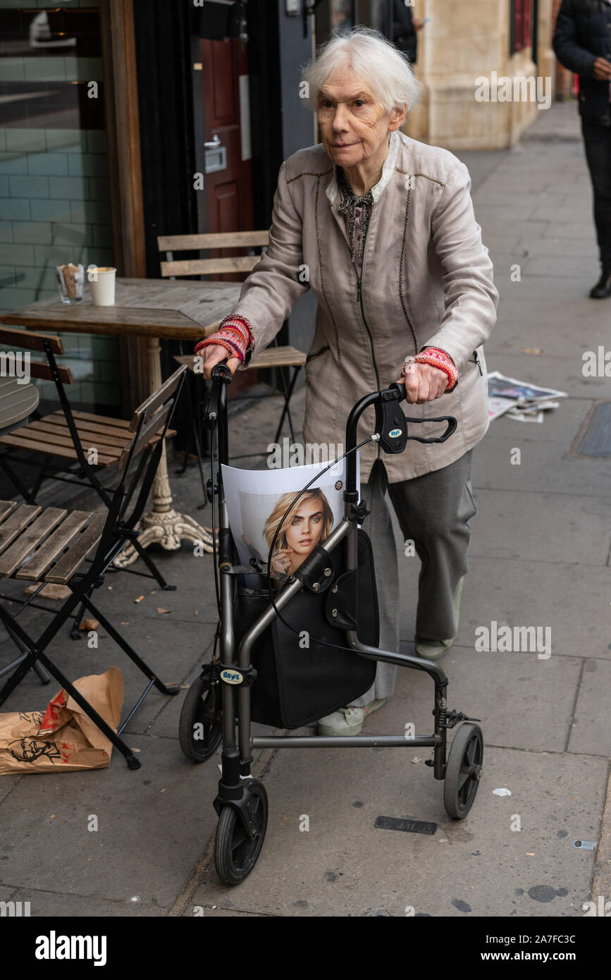 Femme âgée avec aide à la marche. À l'intérieur de l'aide à la marche, un magazine peut être vu. Banque D'Images