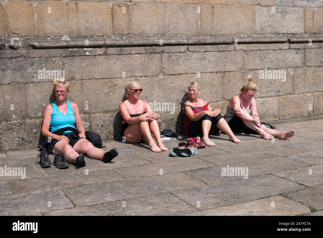 Santiago de Compostela, Espagne ; le 7 juillet 2019 : Groupe de femmes mûres touristes reposant sur pavage en pierre avec la peau brûlée. Les dommages du soleil concept Banque D'Images