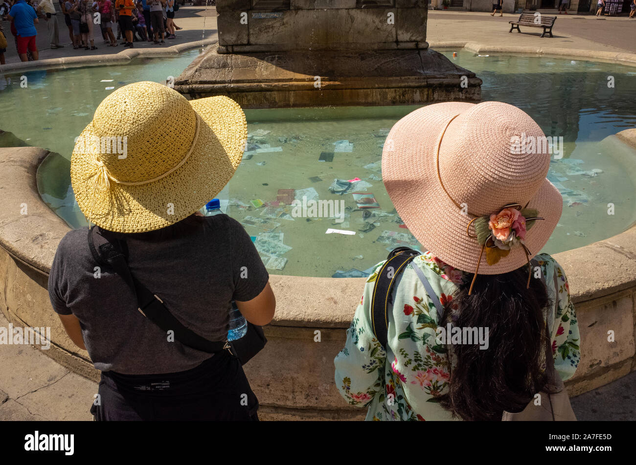 Deux dames s'arrêtent à une fontaine à Arles habillé en vêtements d'été et hat. France Banque D'Images