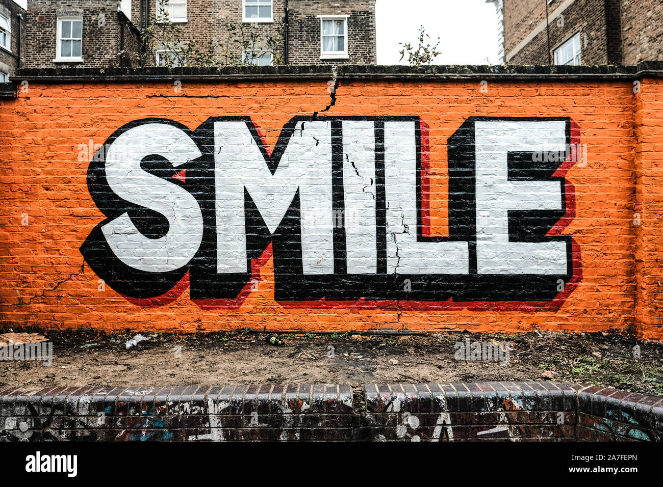 Graffiti sur un mur de brique fissurée à Ladbroke Grove, London.Le message juxtaposées sur la base des environs travaillent bien ensemble Banque D'Images