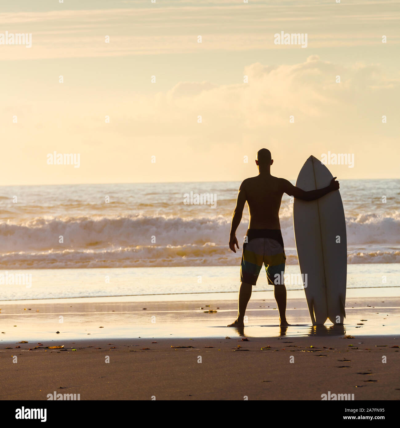 Surfeur sur la plage holding est de surf et les vagues de contrôle Banque D'Images