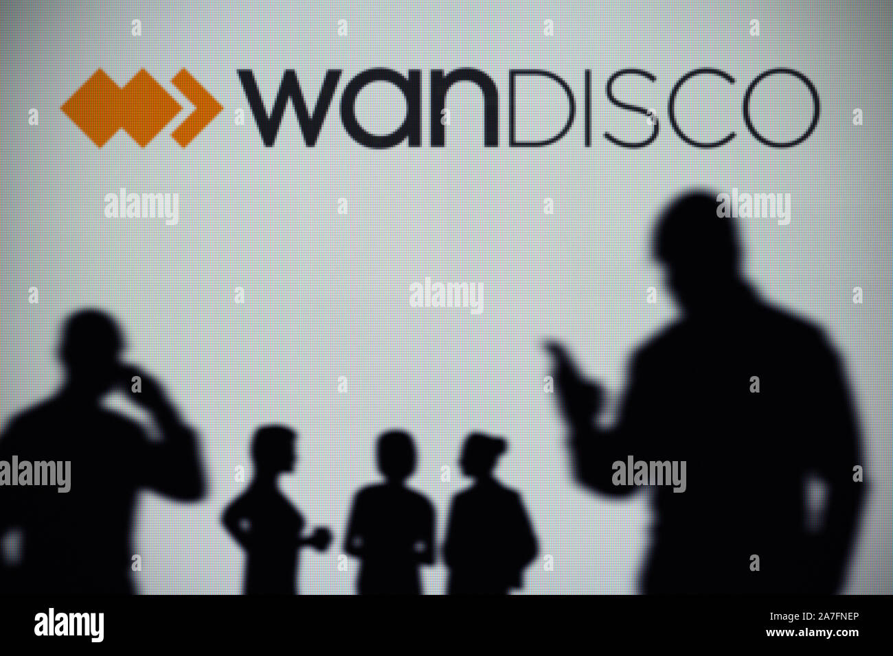 Le logo WANdisco est vu sur un écran LED à l'arrière-plan tandis qu'une silhouette personne utilise un smartphone (usage éditorial uniquement) Banque D'Images