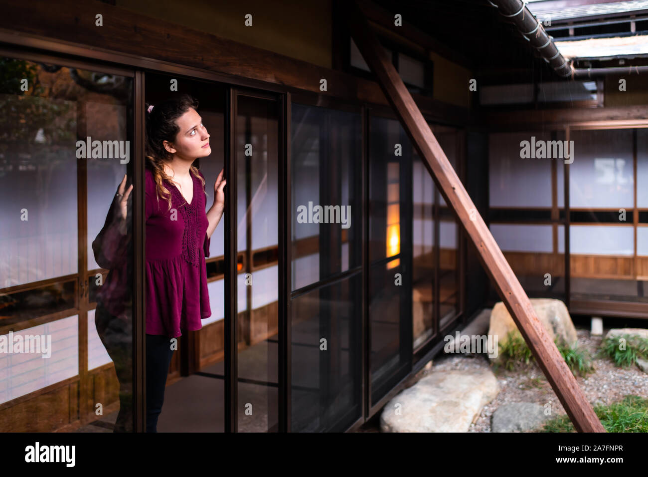 Jeune femme debout à la fenêtre ouverte par porte coulissante sur le jardin japonais intérieur Japon traditionnel avec du gravier dans les rochers en pierre chambre Banque D'Images