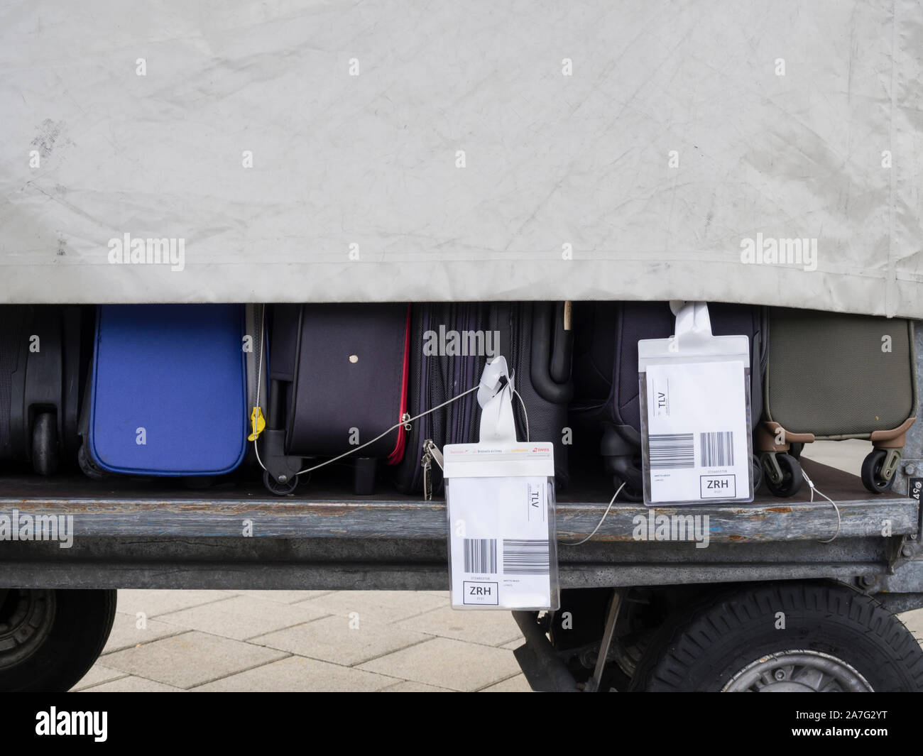 Chariot à bagages de l'aéroport chargé avec des valises à l'extérieur sur un aérodrome. Valises que partiellement visible sous bâche. Banque D'Images