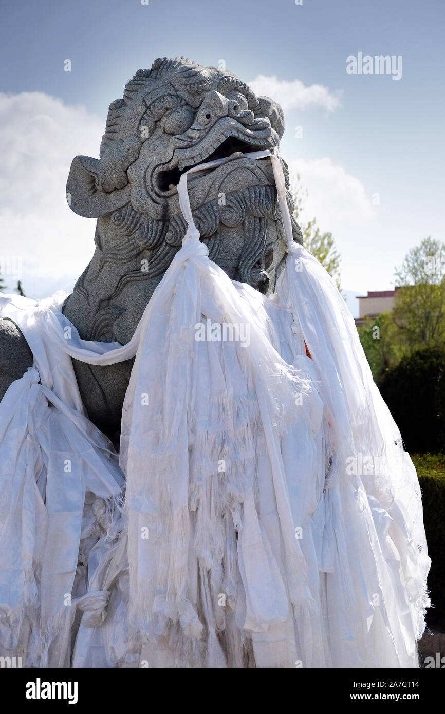 Lion statue devant le Palais du Potala à Lhassa, Tibet, foulards blancs de cérémonie tenue dans sa bouche. Banque D'Images