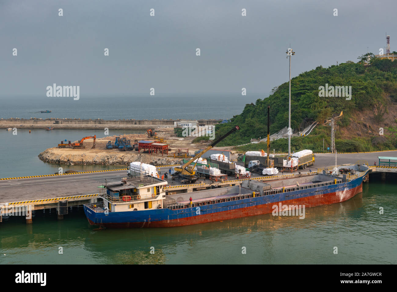 Da nang, Vietnam - 10 mars 2019 : Tien Sa Port dans la baie de Da Nang. Petit bleu-rouge river cargo accoste au quai. Charge grues jaune sac blanc, mettre dans un Banque D'Images