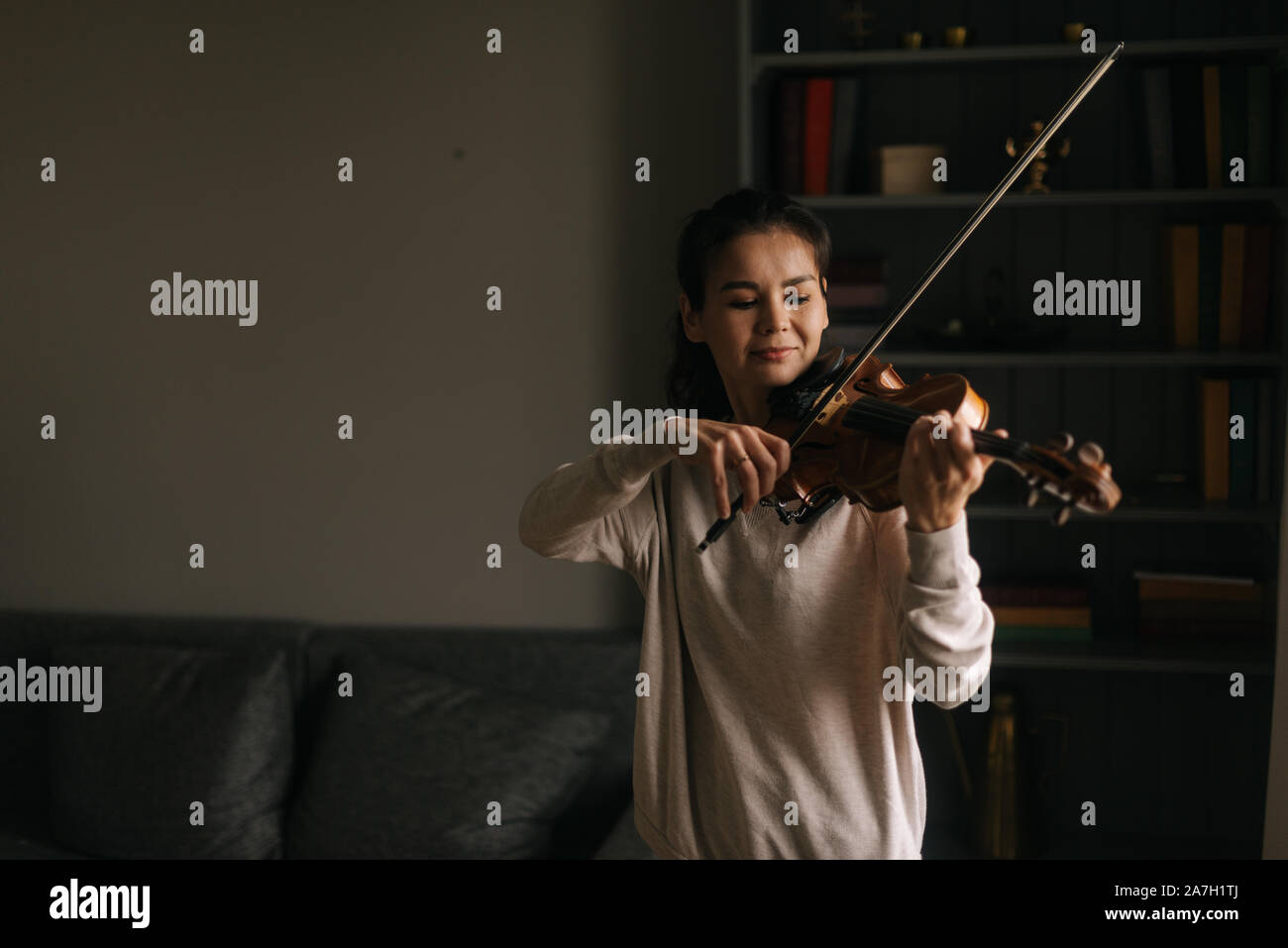 Belle jeune femme joue du violon à la maison Banque D'Images