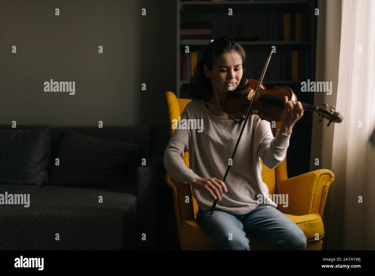 Belle jeune femme joue du violon assis sur chaise soft Banque D'Images