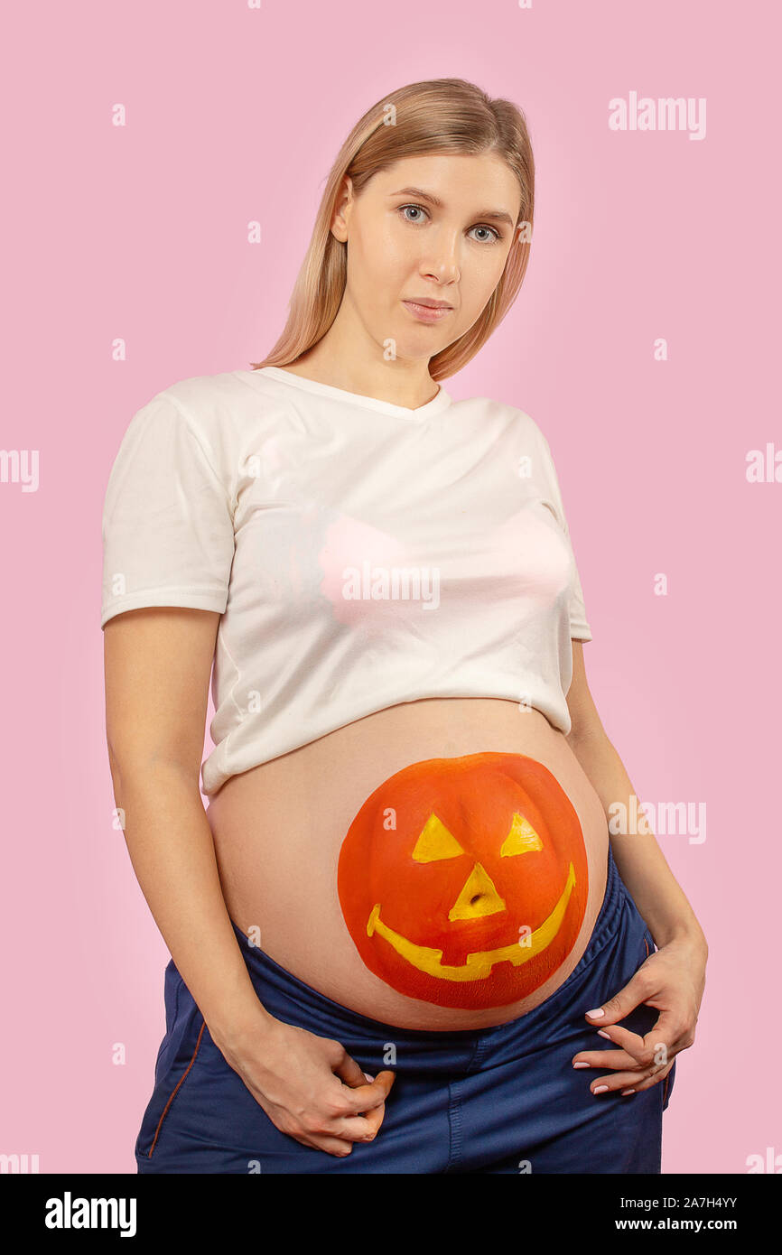 Jeune femme enceinte avec halloween citrouille peinte sur son estomac Banque D'Images