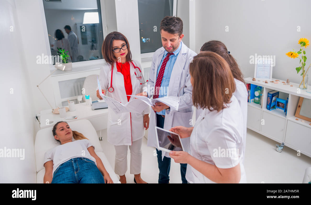 Groupe de médecins debout à côté d'un malade et d'examiner les causes de sa maladie. Banque D'Images