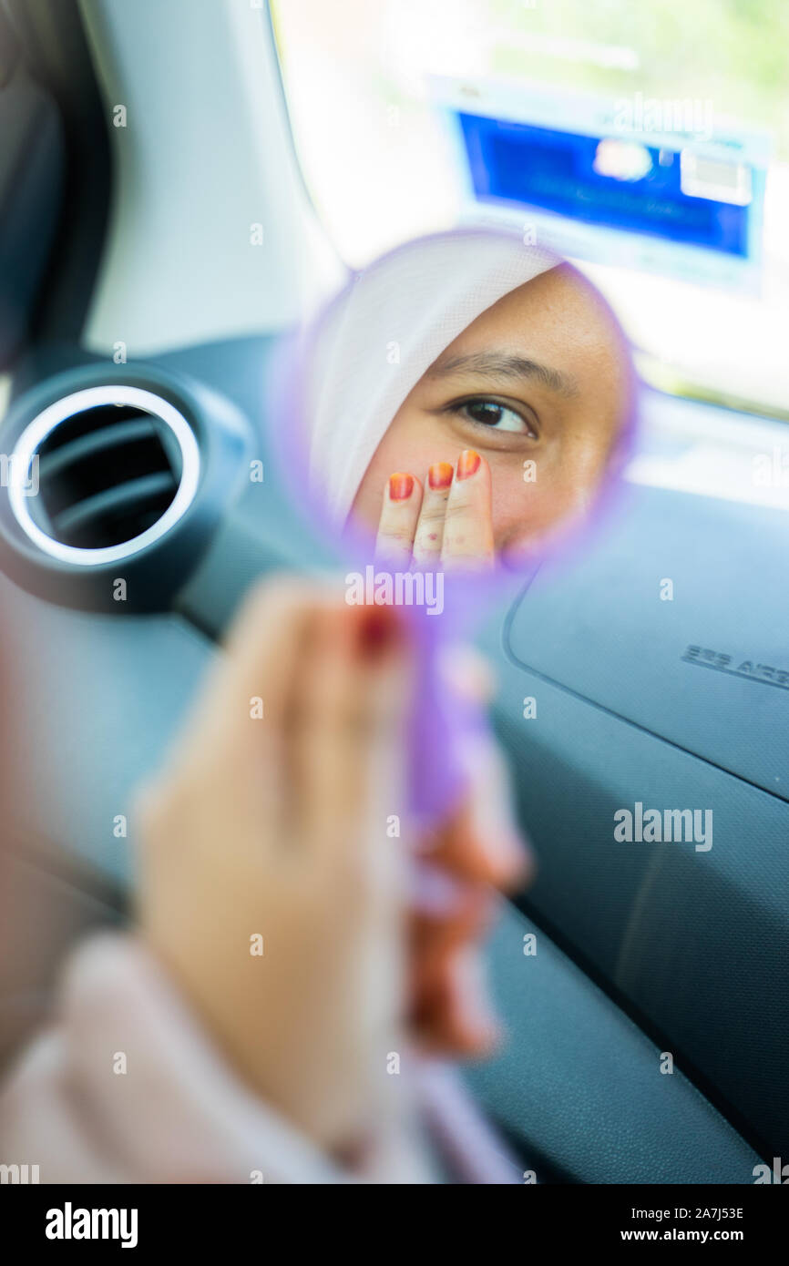 Une fille contrôler ses yeux avec son petit miroir dans une voiture Banque D'Images