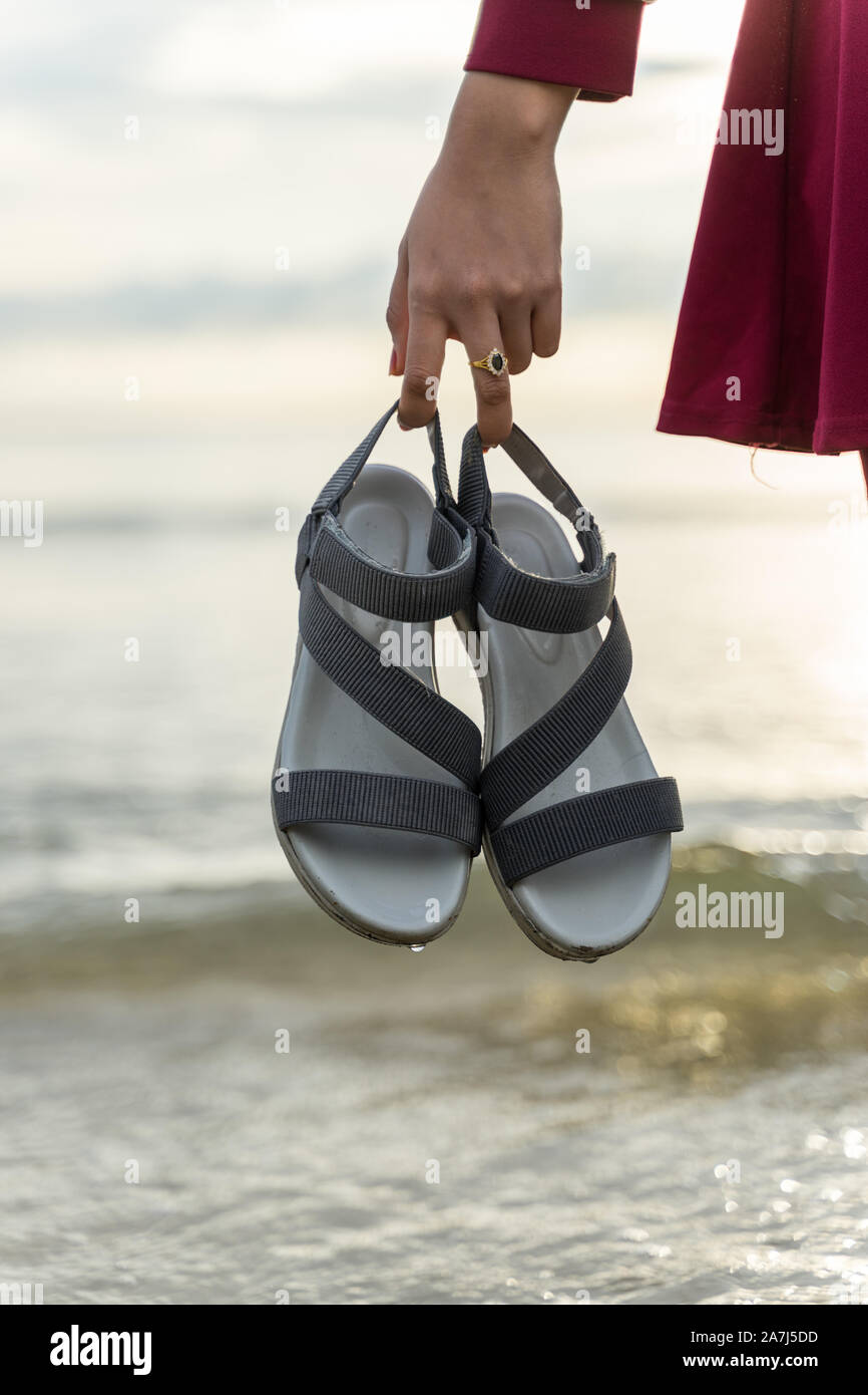 Une jeune fille transportant ses sandales pour éviter de se mettre à l'eau  tout en jouant sur la plage Photo Stock - Alamy