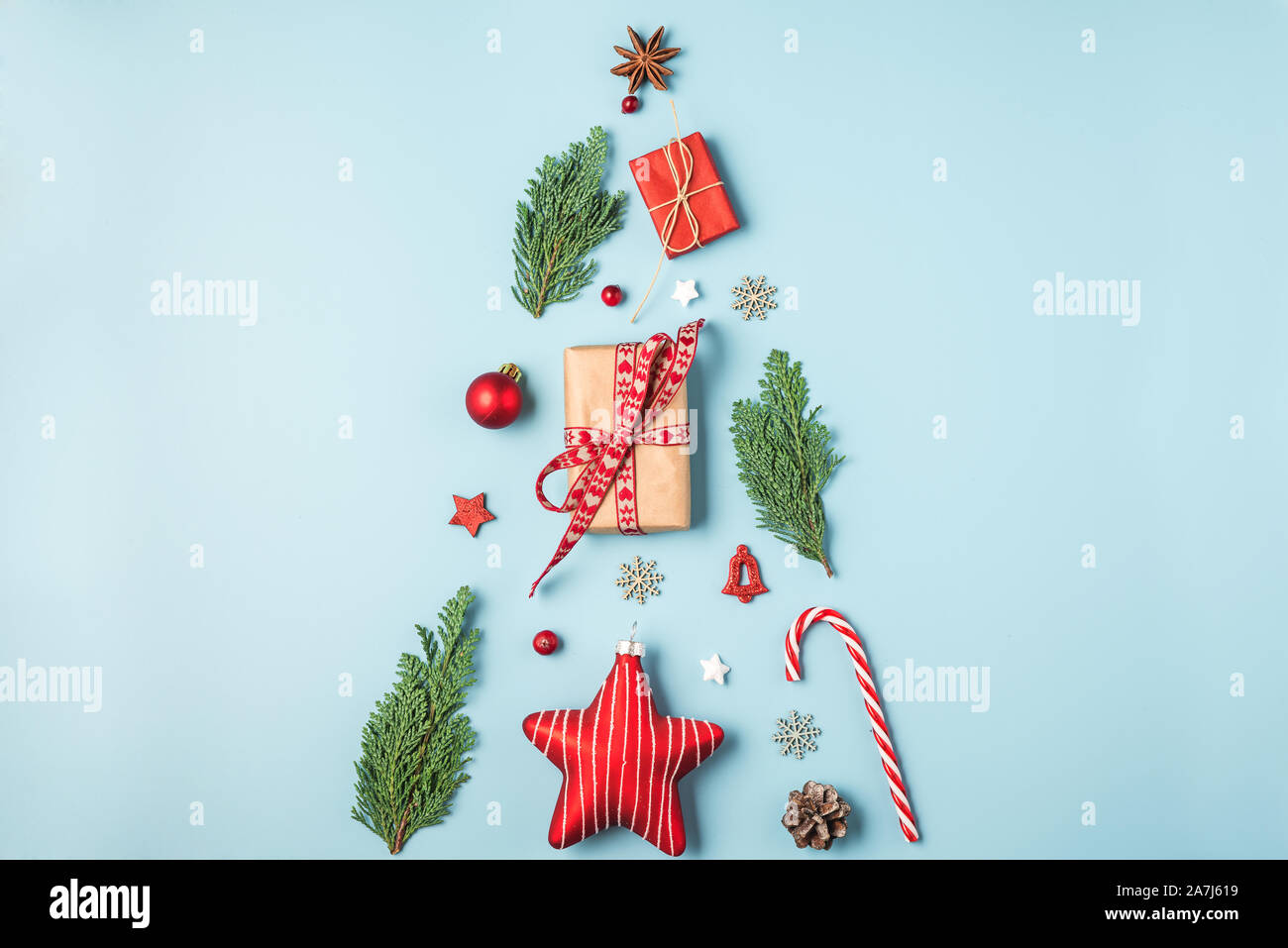 Arbre de Noël à partir de branches de sapin rouge, décorations, bonbons, cadeaux et baies d'hiver sur fond bleu. maison de vacances concept créatif ou nouvel an. Banque D'Images
