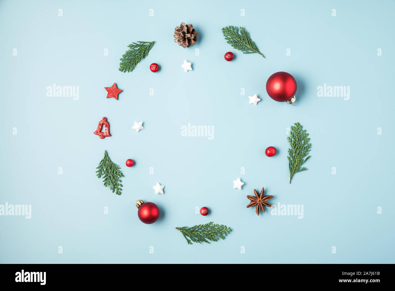 Couronne de noël faites de branches de sapins, décorations rouges, baies d'hiver, pommes de pin sur fond bleu. L'hiver, Noël, nouvel an concept. Télévision Banque D'Images
