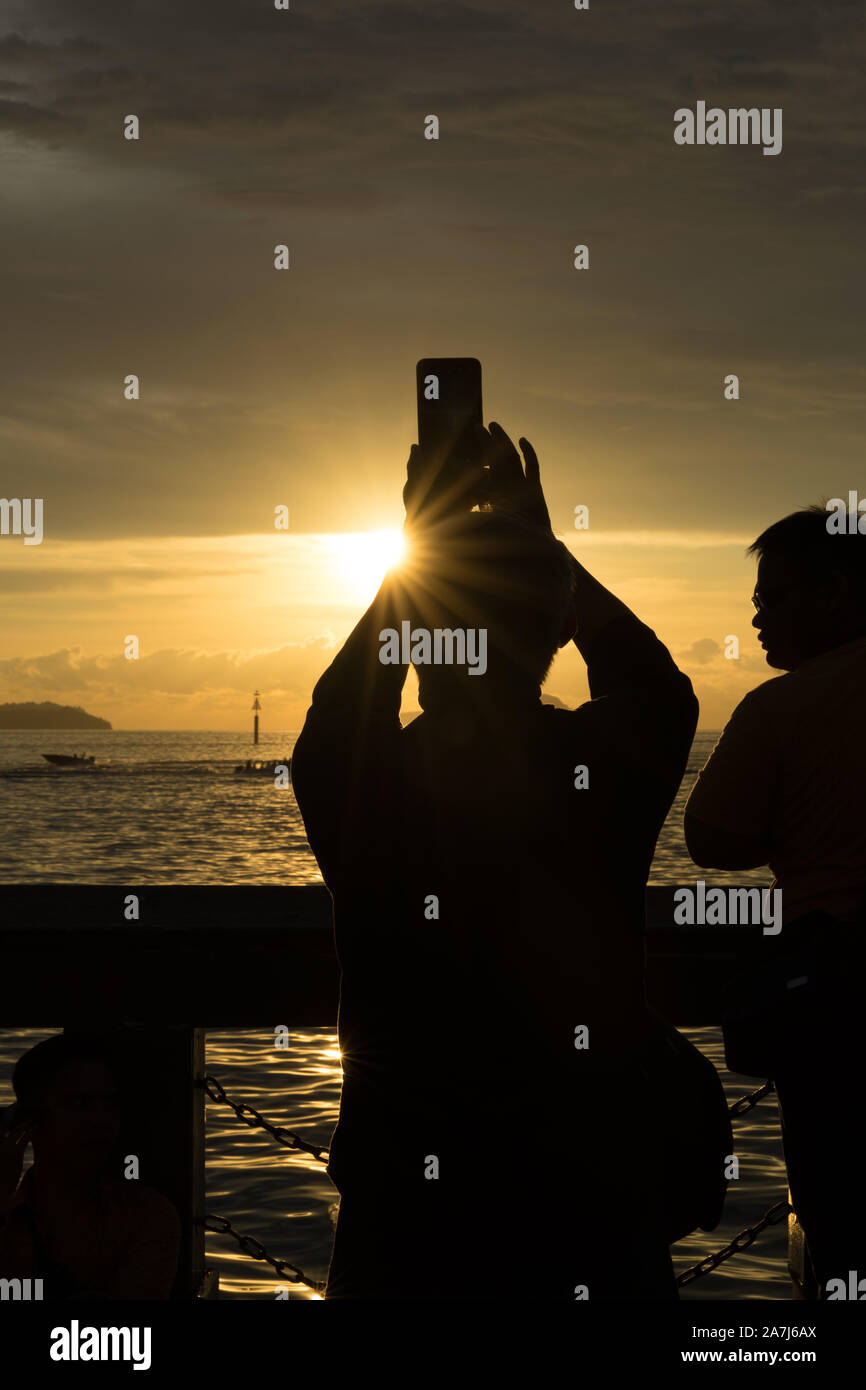 Un couple de personnes dans l'ombre de photographier le coucher du soleil Banque D'Images