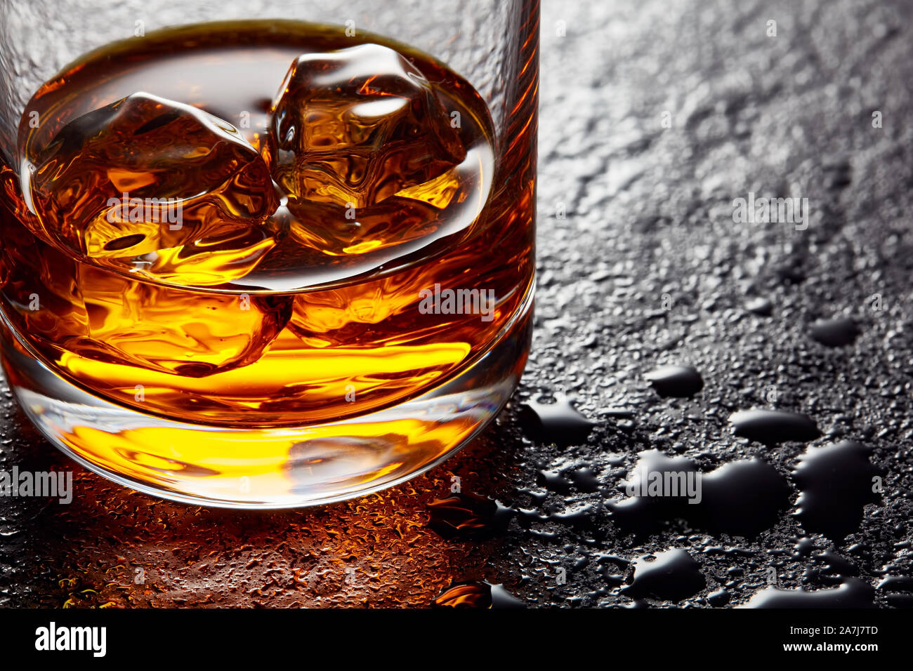 Verre de whisky élégant avec des cubes de glace sur la table en pierre noire. Moody vue rapprochée Banque D'Images