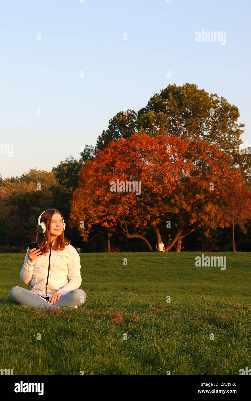 Teenage girl est à l'écoute de la musique à partir de son smartphone en saison automne parc Banque D'Images