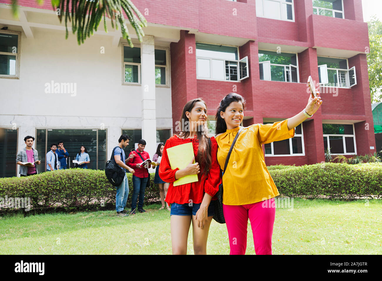 Deux jeunes filles d'université amis étudiants prenant des photos avec selfies smart phone at college Campus Banque D'Images