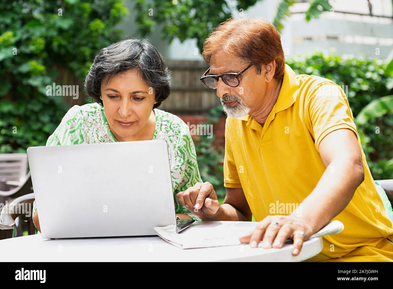 Couple de personnes âgées à la recherche d'écran de l'ordinateur portable dans le jardin de la maison le matin d'été Banque D'Images