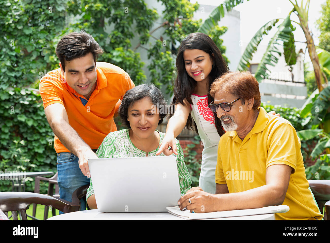 Famille indienne heureux parents hauts et des adultes avec fils-fille-pointage à l'écran du portable au-cour intérieure Banque D'Images